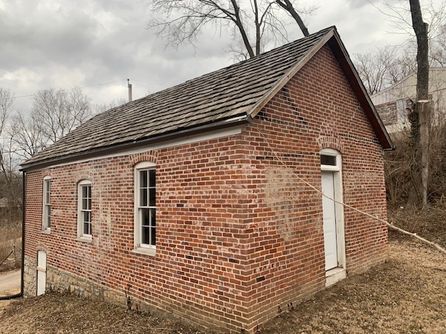 A brick building with three windows and a front door.