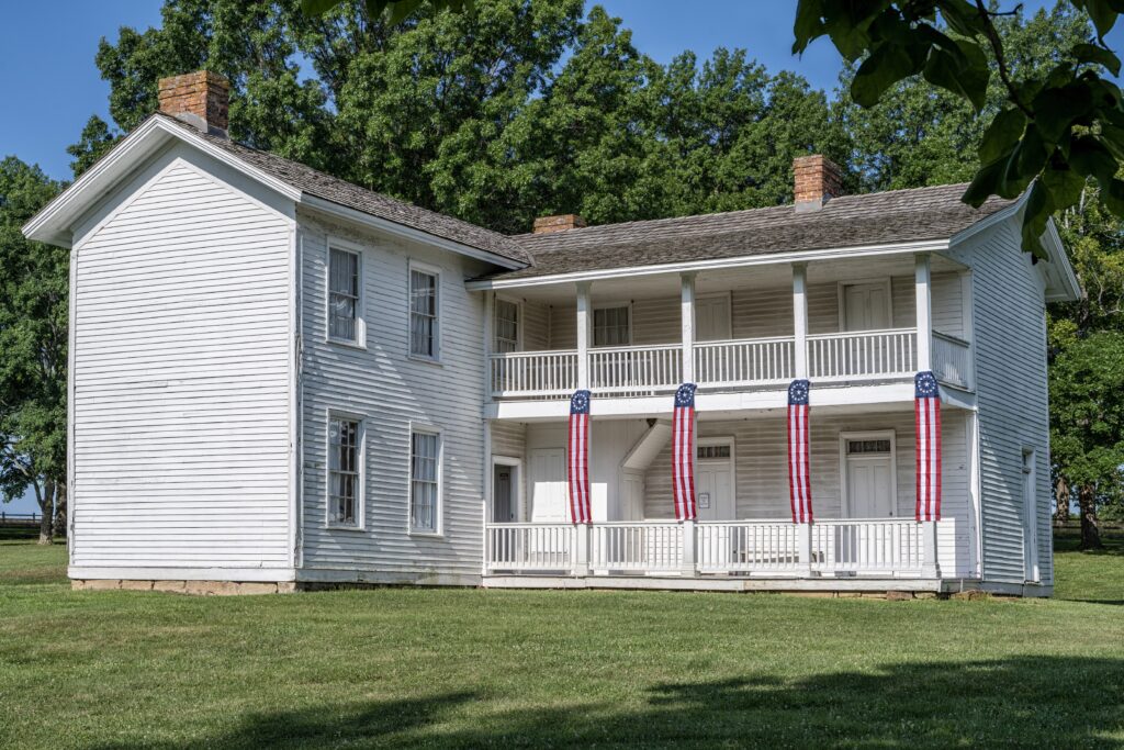 Two story L-shaped white colonial-style house.