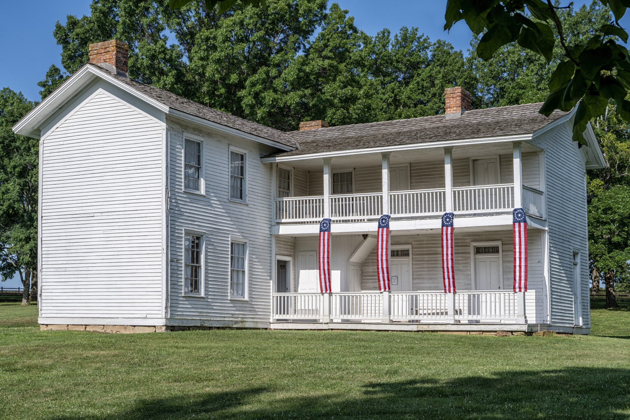 Two story L-shaped white colonial-style house.