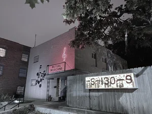 Two story building with a neon treble clef and a sign that says "Mutual Musicians"