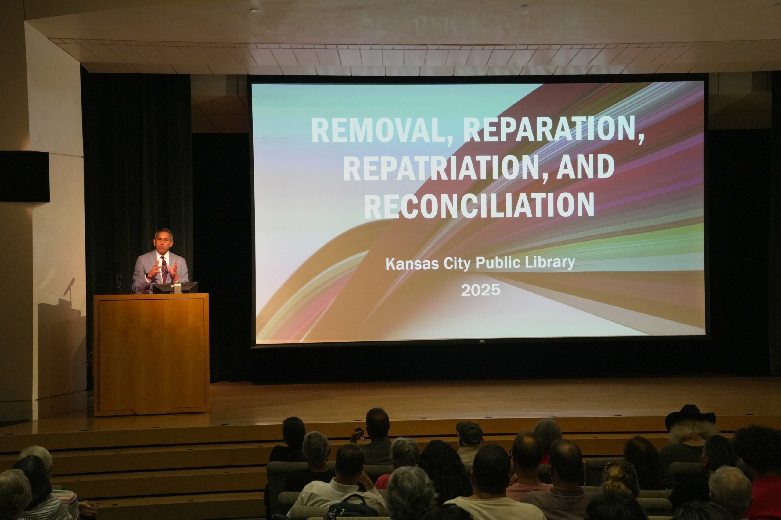 Man giving a talk on "Removal, Reparation, Repatriation, and Reconciliation."