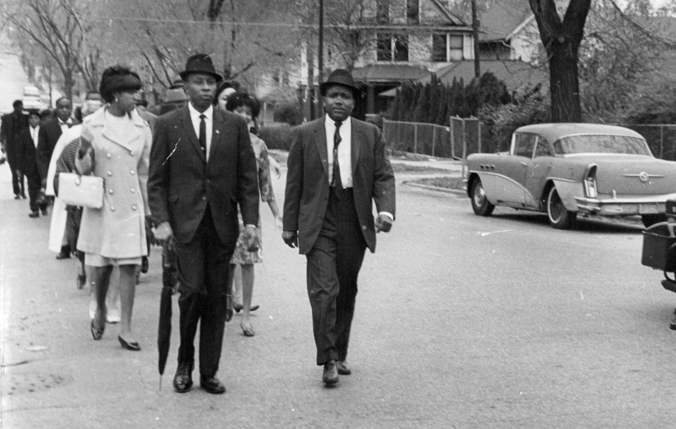 A groups of well dressed Black men and women walk down the street