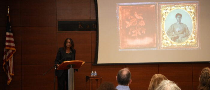 Woman stands at podium with presentation behind her